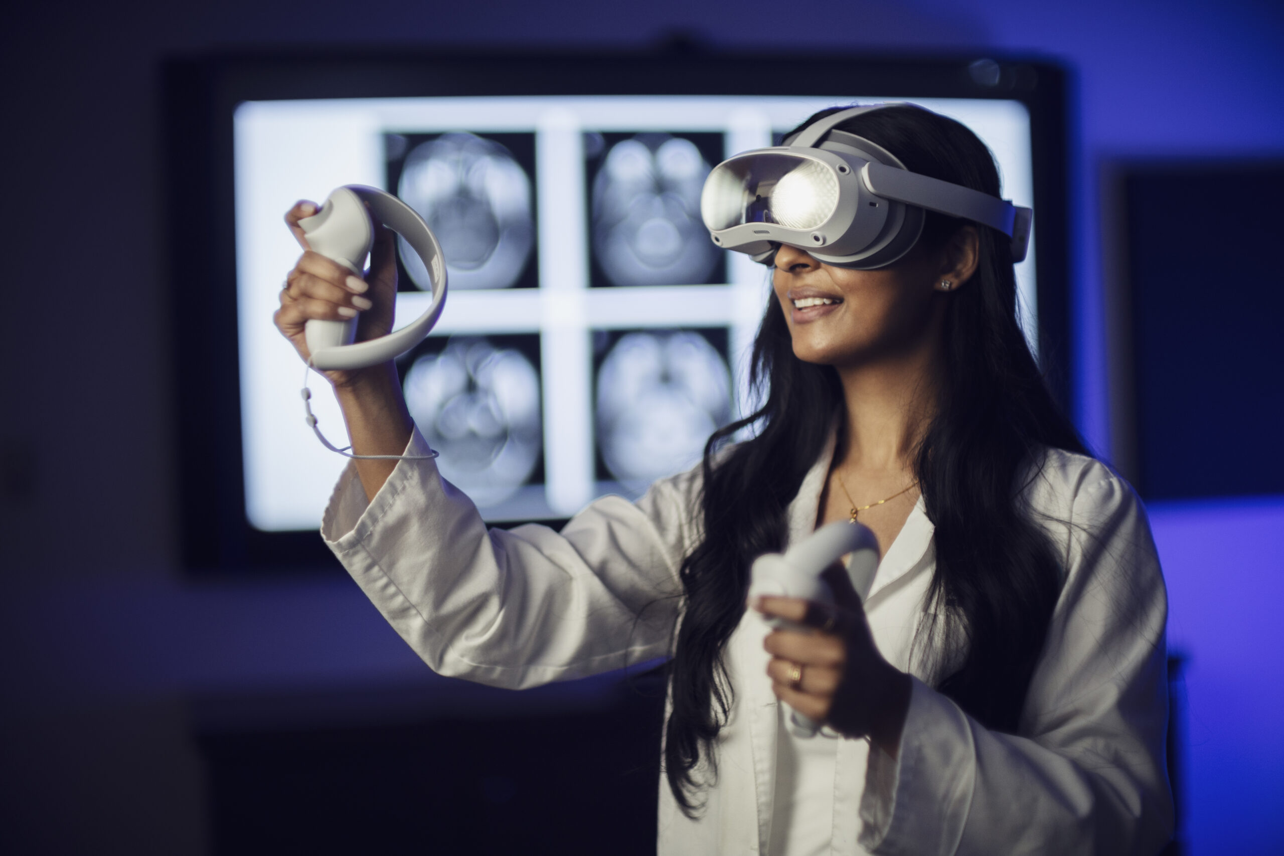 Woman in white lab coat wearing VR headset, holding up both hands with interactive controllers.